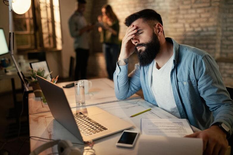 movilllexhausted-businessman-holding-his-head-pain-while-working-late-office (2) (1)